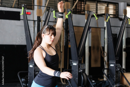 Young woman training on a ski erg machine at a gym, focusing on strength, fitness, and active lifestyle