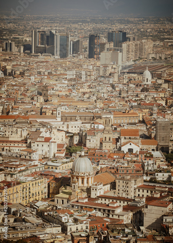 Panoramic view of the old town of Naples, Italy, with historic buildings, rooftops, and the Bay of Naples seen from the Sant'Elmo castle viewpoint