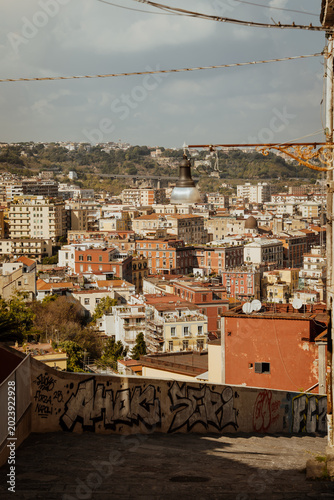 Panoramic view of the old town of Naples, Italy, with historic buildings, rooftops, and the Bay of Naples seen from the Sant'Elmo castle viewpoint
