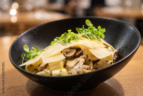 Creamy Mushroom Tagliatelle Pasta with Parmesan Flakes and Microgreens, gourmet plate.
