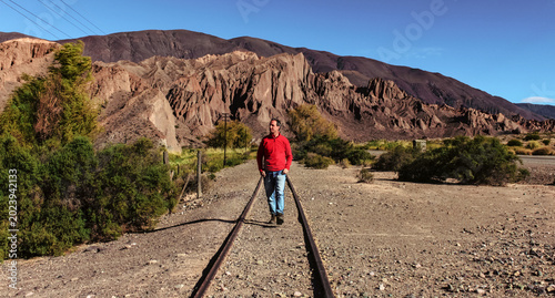 Historic mountain railway tracks running through a deep arid canyon in the Andes.