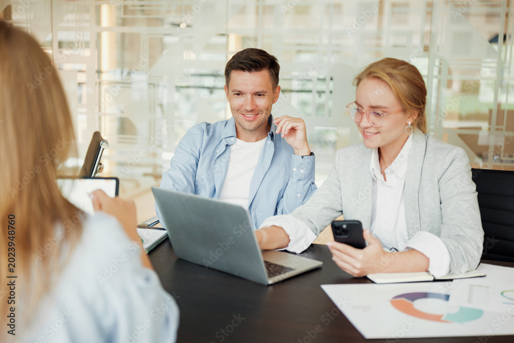Obraz premium Team members engage in a dynamic brainstorming session with laptops and smartphones at a modern office in the afternoon