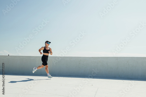 Fotografie Energetic runner sprinting against a clear blue sky on a bright sunny day in a m