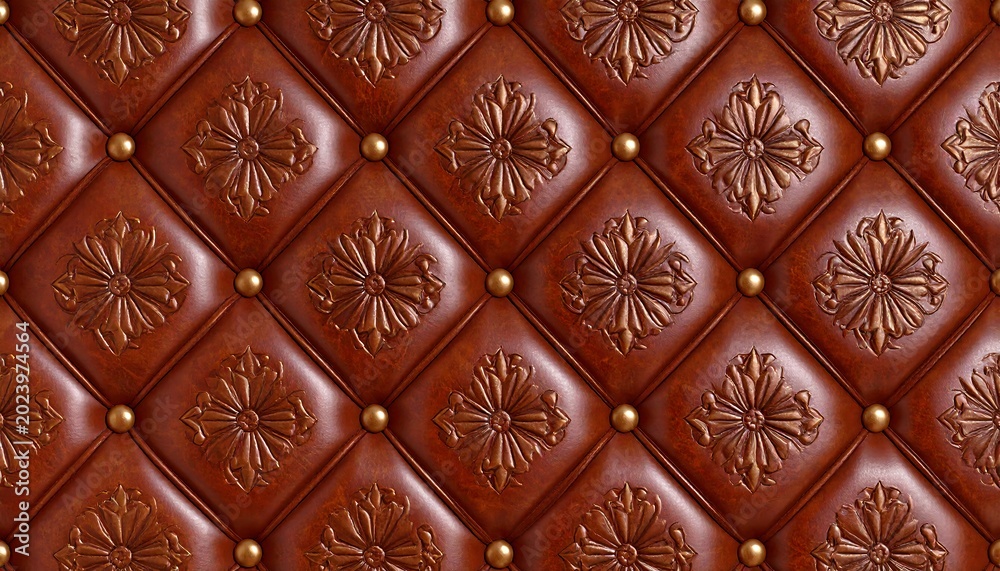Fototapeta premium Detailed close-up view of a brown leather wall panel. Intricate, embossed floral patterns and diamond-shaped quilting, accented by brass-colored studs. A rich, luxurious design