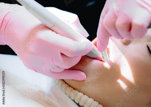 The hands of a dentist remove tartar from a young girl patient.