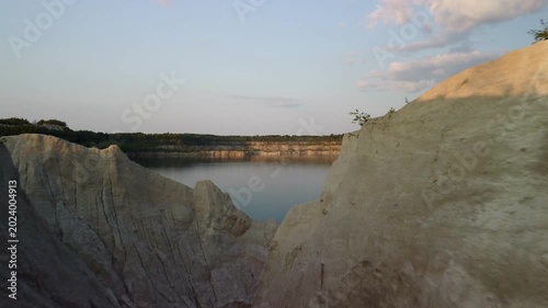 Aerial panoramic view of scenic emerald lake inside a deep clay quarry at twilight.