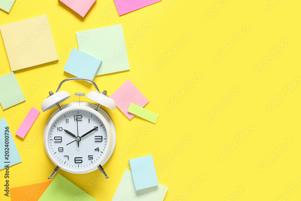 Fototapeta premium Alarm clock with sticky notes on yellow background. Time management concept
