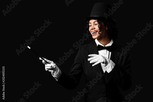Fotografía Young African-American magician with magic wand on black background
