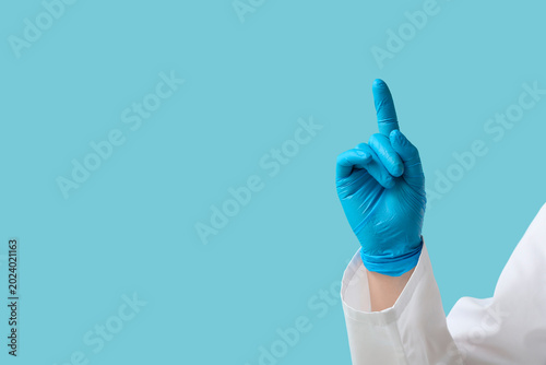 Tableau sur toile Doctor's hand pointing at something on blue background, closeup