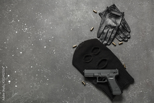 Canvas Print Balaclava with gloves, gun and bullets on dark background with space for text