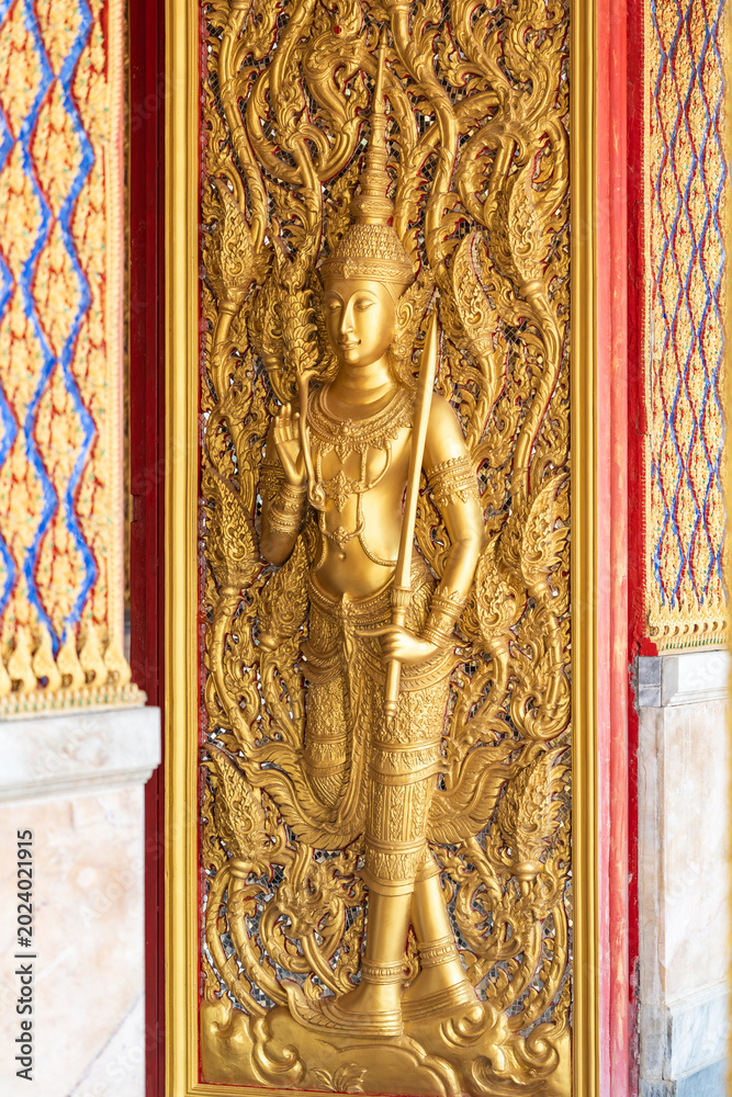Fototapeta premium High relief guardian figure temple door Prasat Thong Kham Kanchanaphisek golden palace Wat Chantharam, ThaSung UthaiThani Thailand gilded ornament mirrored mosaic.