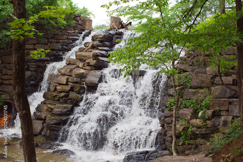 Tableau sur toile Tranquil Forest Waterfall Cascading Over Layered Rock Steps Surrounded by Greenery in Chewacla State Park Auburn, AL