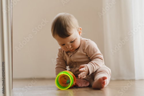 A young child plays with an educational toy. The sun is shining through a window, creating a warm atmosphere. Concept of teething period, baby care, early development, and healthy childhood life