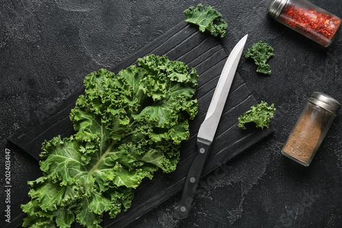 Bild auf Leinwand Cutting board with fresh leaves of kale cabbage and spices on black background