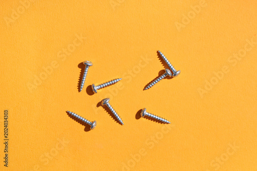 Pile of screws on orange ba...