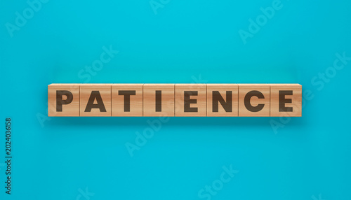 Photos Patience Word Blocks: Wooden blocks with the word PATIENCE printed on them, arranged in a straight line against a vibrant teal background, symbolizing a virtue