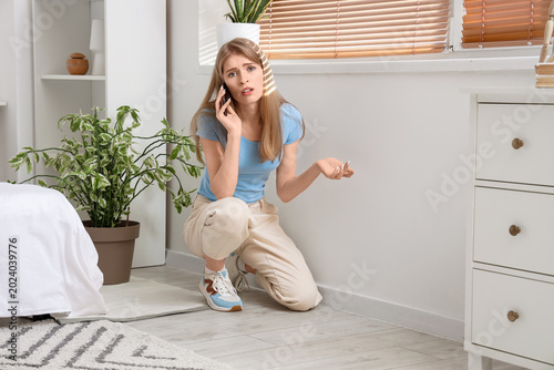 Fotografía Young woman with mold on wall talking by mobile phone in bedroom