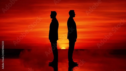 Two Silhouetted Men Back To Back Facing Fiery Sunset Over Reflective Water Surface Vivid Orange Sky