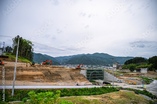Tableau sur toile 山を背景に複数の重機が稼働する、大規模な道路・トンネル建設工事現場の全景風景。 / Panoramic view of a large-scale road and tunnel construction site with heavy machinery and mountains