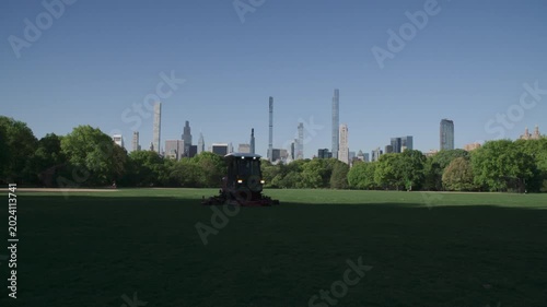 Handheld shot of a groundskeeper mowing the lawn in Central Park