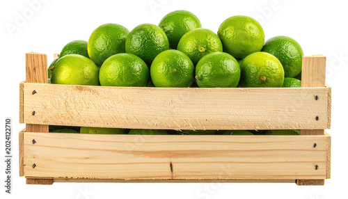 Crate full of ripe, green limes against a dark background