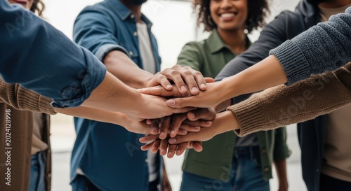 Diverse group of people stacking hands together in a symbol of teamwork and unity
