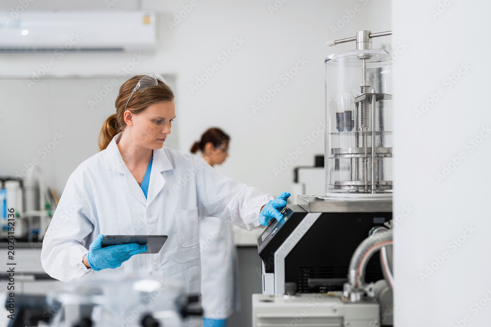 Naklejka premium Female scientist with tablet operating high tech equipment in laboratory, clinical research specialist working on scientific experiment, medical biotechnology analysis, pharmaceutical development.