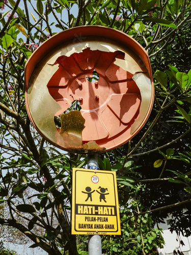 Bild auf Leinwand Damaged outdoor convex safety mirror with pedestrian children warning sign in Yo