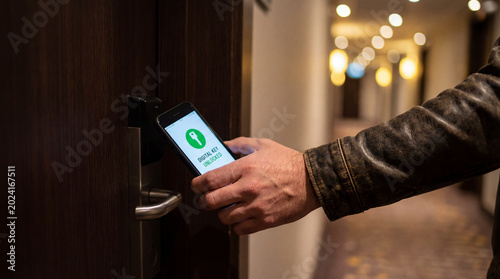 Hand using smartphone digital key to unlock hotel room door in hallway for contactless access smart hospitality security mobile check in concept for modern travel convenience guest experience