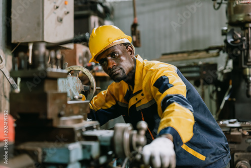 Tableau sur toile Professional African black Engineer male worker work with metal lathe machine in