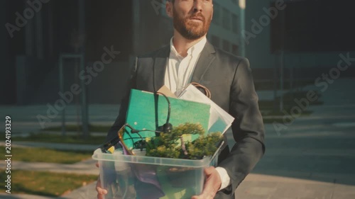 Disheveled executive walks with uncertain purpose, Office worker carries belongings through quiet evening surroundings