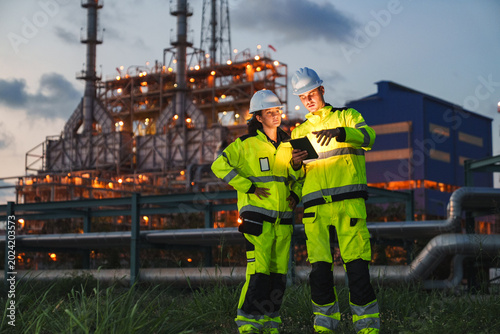 Oil and gas refinery in petroleum industry, industrial plant engineer worker safety inspection tablet refinery night facility pipeline