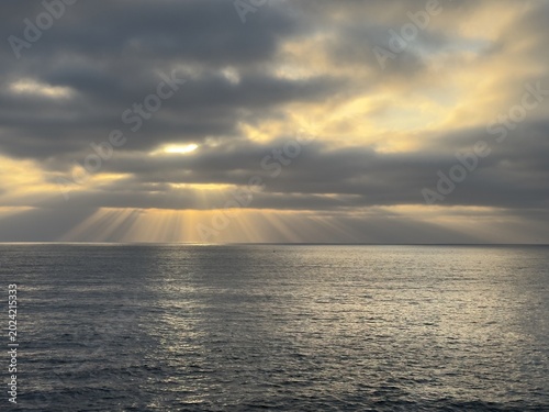 Fotografie An exceptional atmospheric display of bold crepuscular light beams pouring down from a highly dramatic stormy cloudscape over the wide open Pacific Ocean in La Jolla, California