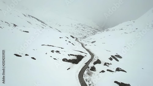 Aerial drone moving back showing the Shingo La Pass road amid snow covered Himalaya mountains during snow fall showing the cold and beautiful environments of Ladakh, Leh, Sissu and Himachal Pradesh