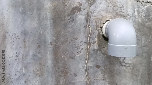 Gray plastic drainage pipe on stained concrete wall. Industrial, plumbing, construction, infrastructure, maintenance, architecture, building, water management, design, technology, abstract concepts.
