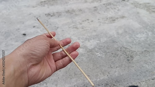 Hand with skewer on concrete. Suitable for food, cooking, grilling, recipes, kitchen, bbq, culinary, textures, backgrounds, and design projects.