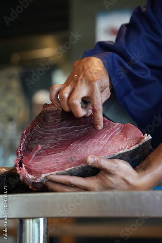 Photos Fresh tuna fish fillet being cut by hand, close-up seafood market photo, raw sashimi-grade meat for culinary and restaurant use
