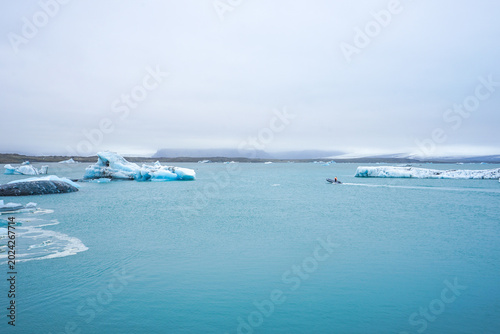 Foto Glacial lagoon with floating icebergs and calm turquoise water under overcast sk