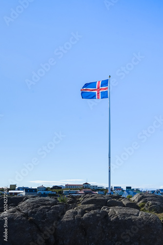 Canvastavla Icelandic flag flying high on a rocky outcrop against a clear blue sky,Iceland
