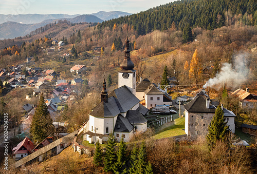 Spania Dolina with historic church, hillside houses, forested slopes, and soft autumn light, Slovakia.