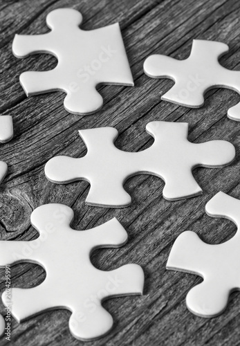 Scattered white jigsaw puzzle pieces on rustic wooden background