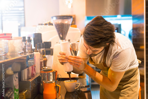 Foto A skilled barista expertly pours steamed milk into a cup, crafting a specialty coffee drink in a bustling cafe environment