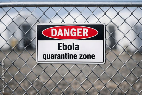 Metal warning sign with text Danger. Ebola quarantine zone. Selective focus on outbreak isolation area near blurred medical tents