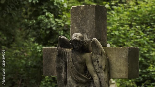 Footage capturing a historic cemetery in London, England surrounded by dense forest vegetation and aged stone ruins. The scene features old gravestones, overgrown pathways, and atmospheric woodland su