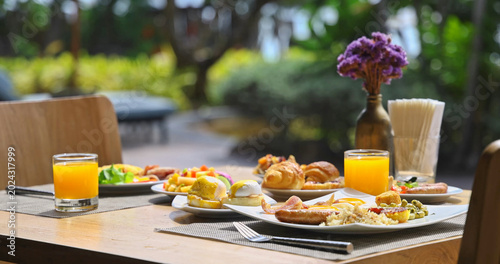 Fotografie Gourmet breakfast spread sitting on wooden table in outdoor terrace with lush tr