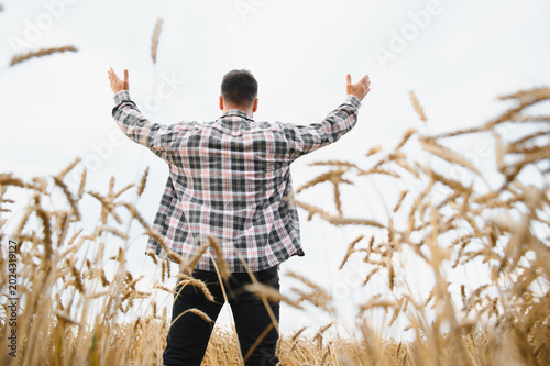 Fotografie Farmer raising arms in wheat field celebrating harvest