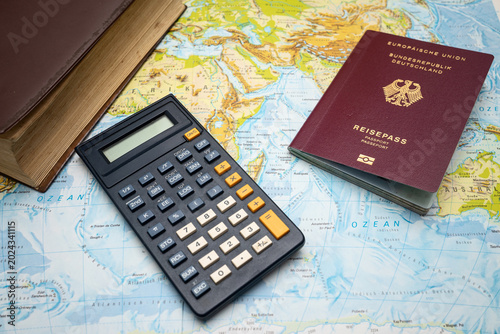 Passport, calculator and book placed on a world map symbolizing vacation planning travel budgeting trip organization holiday preparation international tourism and time management