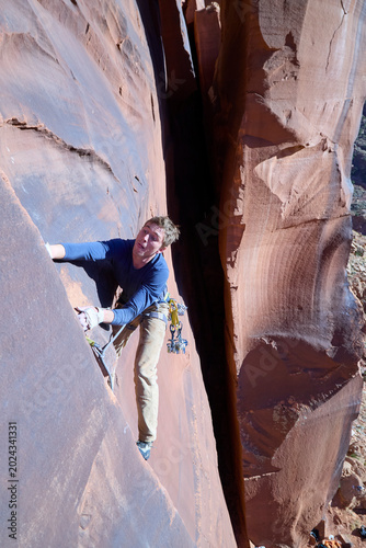 Canvas-taulu Rock climber battling difficult sandstone crack in canyon