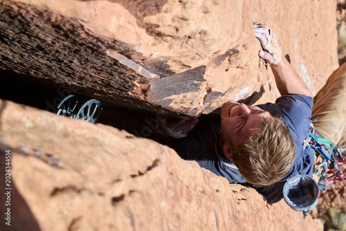 Valokuva Rock climber battling a crack on sandstone cliff