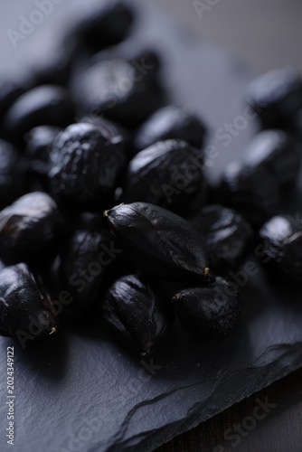 Black Garlic Cloves on Dark Slate